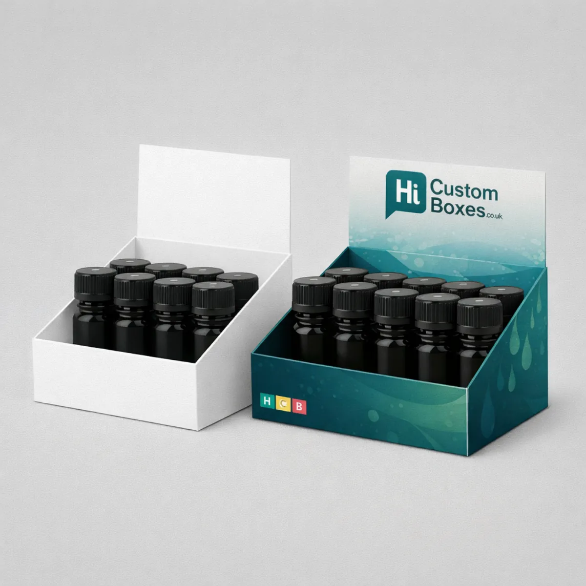 Two counter-top display boxes holding small black bottles- one plain white and one with teal branding- class=